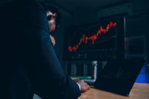 Thoughtful focused successful caucasian male stock investor, broker, financial adviser, sits at work desk, looks at computer, pensively analyze risks and prospects, rise or fall of cryptocurrency coin photo