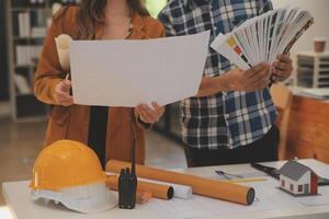 masculino y hembra industrial ingenieros en difícil sombreros discutir nuevo proyecto mientras utilizando ordenador portátil. ellos hacer demostración gestos ellos trabajo en un pesado industria fabricación fábrica. foto