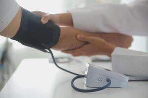 Male doctor uses a blood pressure monitor to check the body pressure and pulse of the patients who come to the hospital for check-ups, Medical treatment and health care concept. photo