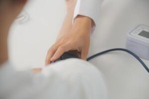 Male doctor uses a blood pressure monitor to check the body pressure and pulse of the patients who come to the hospital for check-ups, Medical treatment and health care concept. photo