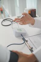 Male doctor uses a blood pressure monitor to check the body pressure and pulse of the patients who come to the hospital for check-ups, Medical treatment and health care concept. photo