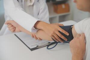 Male doctor uses a blood pressure monitor to check the body pressure and pulse of the patients who come to the hospital for check-ups, Medical treatment and health care concept. photo