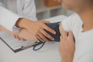 masculino médico usos un sangre presión monitor a cheque el cuerpo presión y legumbres de el pacientes quien ven a el hospital para chequeos, médico tratamiento y salud cuidado concepto. foto