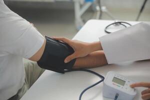 Male doctor uses a blood pressure monitor to check the body pressure and pulse of the patients who come to the hospital for check-ups, Medical treatment and health care concept. photo