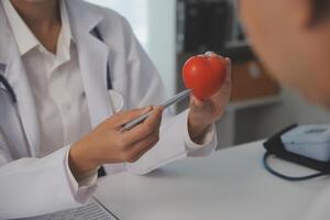 manos de médico mujer participación rojo corazón, demostración símbolo de amar, humano apoyo a paciente, promoviendo médico seguro, temprano chequeo para cuidado de la salud, cardiólogo ayuda. cerca arriba de objeto foto