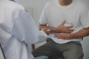 Man suffering with severe stomach pain sitting at home. Hand of mature guy holding abdomen suffering from ache, diarrhea or indigestive problem. Caucasian guy pressing on belly on painful sensation photo
