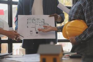 A team of construction engineers talks to managers and construction workers at the construction site. Quality inspection, work plan, home and industrial building design project photo