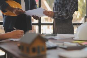 A team of construction engineers talks to managers and construction workers at the construction site. Quality inspection, work plan, home and industrial building design project photo