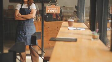 Startup successful small business owner sme beauty girl stand with tablet smartphone in coffee shop restaurant. Portrait of asian tan woman barista cafe owner. SME entrepreneur seller business concept photo