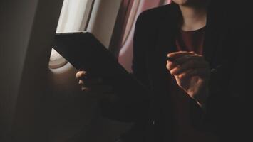 Blonde female tourist checking incoming notification on smartphone sitting on seat of airplane with netbook.Young businesswoman share media from telephone on laptop computer during plane flight photo