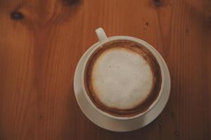 Coffee in white cup on wooden table, with spoon. photo