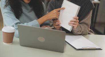 asiático mujer de negocios trabajando en ordenador portátil computadora Mira para trabajo en línea, Lanza libre mirando y mecanografía en cuaderno en mesa, estilo de vida de mujer estudiando en línea foto