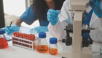 biochemical research scientist team working with microscope for coronavirus vaccine development in pharmaceutical research labolatory, selective focus photo