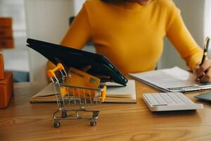 mujer joven dueña de una pequeña empresa comprando en línea en casa. tomando nota de los pedidos de los clientes con teléfonos móviles. pyme emprendedor o concepto de estilo de vida independiente. foto