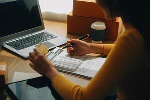 Young woman holding a smartphone, tablet showing payment success and credit card with yellow parcel box as online shopping concept in office photo