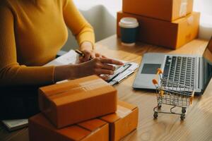 Young woman holding a smartphone, tablet showing payment success and credit card with yellow parcel box as online shopping concept in office photo