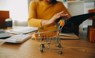 mujer joven dueña de una pequeña empresa comprando en línea en casa. tomando nota de los pedidos de los clientes con teléfonos móviles. pyme emprendedor o concepto de estilo de vida independiente. foto