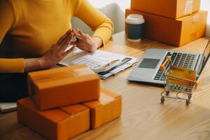 mujer joven dueña de una pequeña empresa comprando en línea en casa. tomando nota de los pedidos de los clientes con teléfonos móviles. pyme emprendedor o concepto de estilo de vida independiente. foto