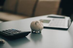 Young Asian woman saving for retirement Saving money through a piggy bank and taking notes on notebook, savings concept. photo