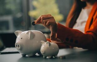 A young girl works at a laptop, writes a business development plan in a notebook, develops a strategy and makes calculations of earned funds. A woman puts her savings in a piggy bank. photo