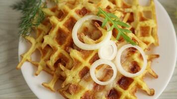 fried potato cheese vegetable waffles with bacon and onions in a plate, on a wooden table. video