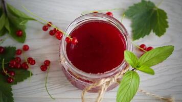 sweet summer jam from ripe red currants in a jar on a wooden table video