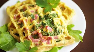 ovo omelete recheado com verduras e linguiça frito dentro a Formato do waffles, em uma de madeira mesa video