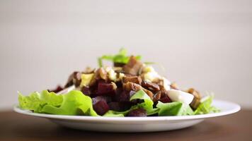 Salat mit gekocht Rüben, gebraten Auberginen, Kräuter und Rucola im ein Platte, auf ein hölzern Tisch. video