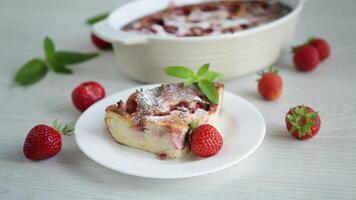 Sweet cottage cheese casserole with strawberry filling, in a plate on a wooden table. video