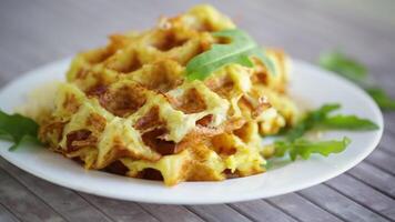 fried potato waffles with cheese in a plate on a light wooden table. video