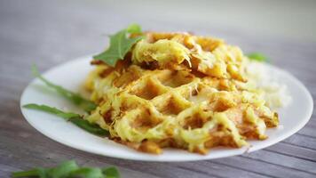 fried potato waffles with cheese in a plate on a light wooden table. video