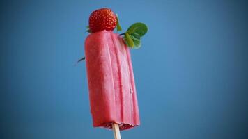 cooked homemade strawberry ice cream on a stick, isolated on blue background video