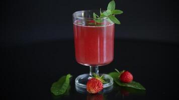 Cold summer strawberry kvass with mint in a glass isolated on black background video