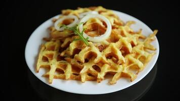 fried potato cheese vegetable waffles with bacon and onion in a plate isolated on black background. video