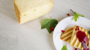 fried bread croutons for breakfast with redcurrant jam in a plate with berries on a wooden table. video