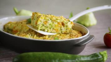 vegetable casserole of patissons, zucchini, carrots in a ceramic form on a light wooden table. video