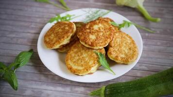 fried vegetable pancakes from squash and zucchini with herbs, on a light wooden table. video