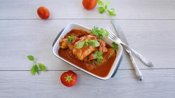 tradicional relleno repollo con picado carne y arroz, servido en un tomate salsa en un de madera mesa . video