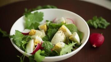 Fresh spring salad with fresh lettuce leaves, radishes, boiled eggs in a bowl video