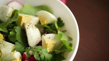 Fresh spring salad with fresh lettuce leaves, radishes, boiled eggs in a bowl video