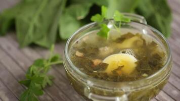 Spring soup from fresh sorrel with boiled eggs in a plate on a wooden table video