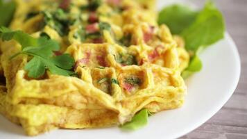 ovo omelete recheado com verduras e linguiça frito dentro a Formato do waffles, em uma de madeira mesa video