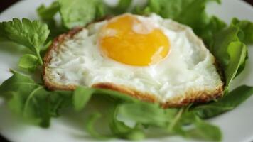 ett friterad ägg med arugula och sallad i en tallrik på en trä- tabell video