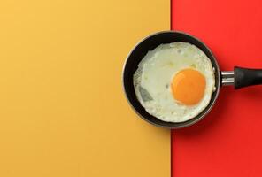 soleado lado huevo en mini pan encima amarillo y rojo mesa foto