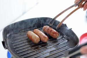 Cooking Process Making Grilled Sausages in the Kitchen photo