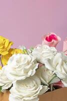 Bouquet of multicolored roses in a box on a pink background for Valentine's Day photo