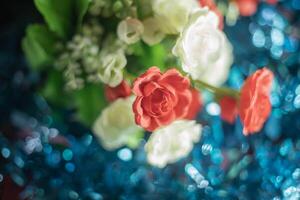 Colorful artificial white and red rose flowers bunch on blue bokeh background. photo