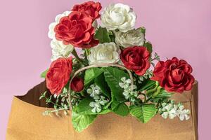 Beautiful bouquet of red and white roses in a paper bag on a pink background photo