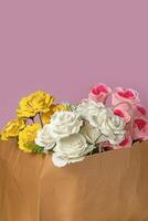 Bouquet of roses in a paper bag on a pink background, close-up photo