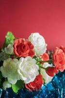 Bouquet of artificial flowers on a red background with copy space. Selective focus photo